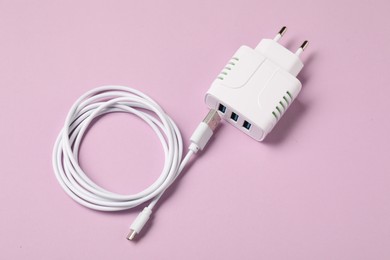 Photo of USB power adapter and charge cable on pink background, above view