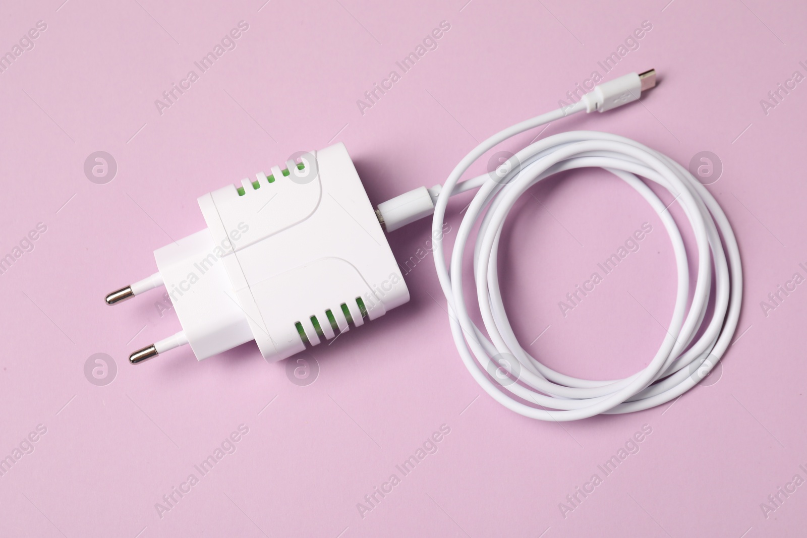 Photo of USB power adapter with charge cable on pink background, top view