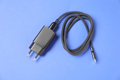 Photo of USB power adapter with charge cable on blue background, top view