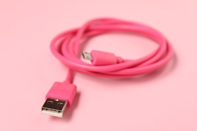 Photo of One USB charge cable on pale pink background, closeup