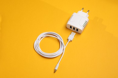 Photo of USB power adapter and charge cable on orange background