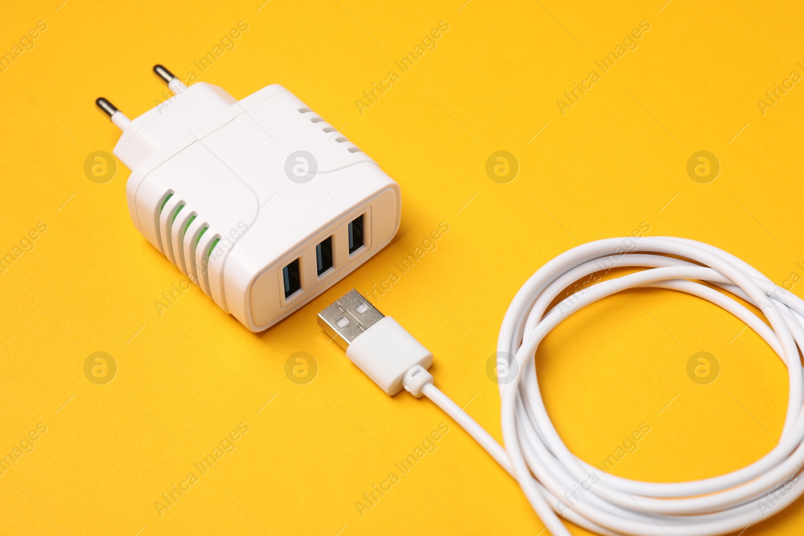 Photo of USB power adapter and charge cable on orange background, closeup