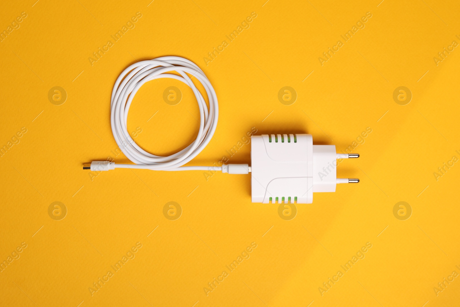 Photo of USB power adapter with charge cable on orange background, top view