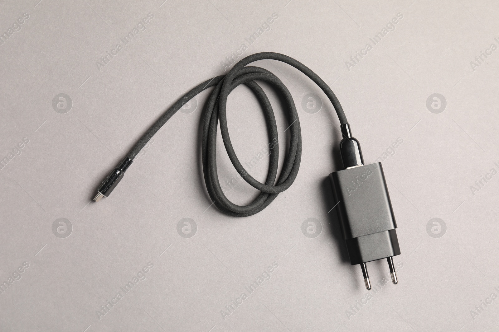 Photo of USB power adapter with charge cable on grey background, top view