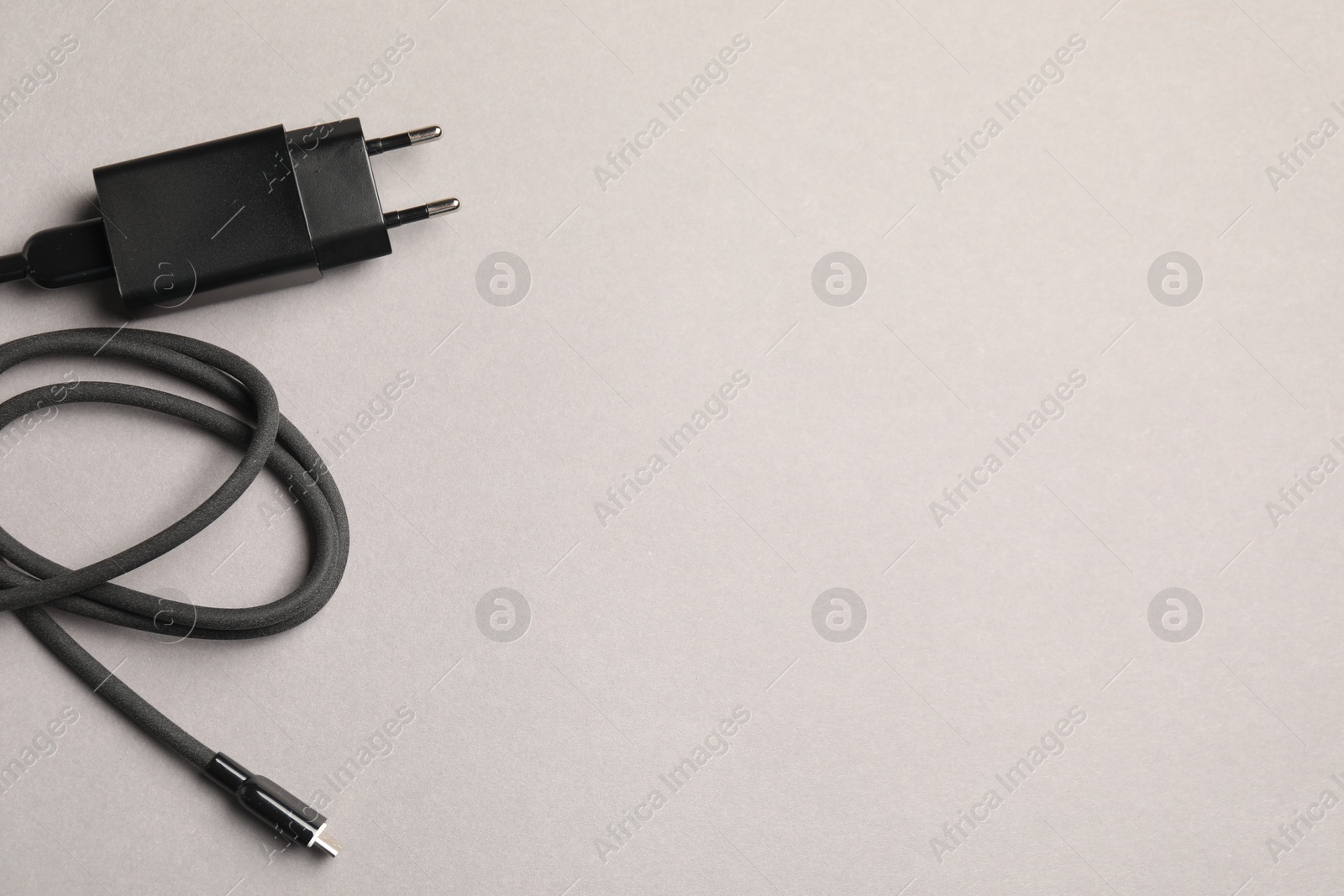 Photo of USB power adapter with charge cable on light grey background, top view. Space for text