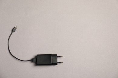 Photo of USB power adapter with charge cable on grey background, top view. Space for text