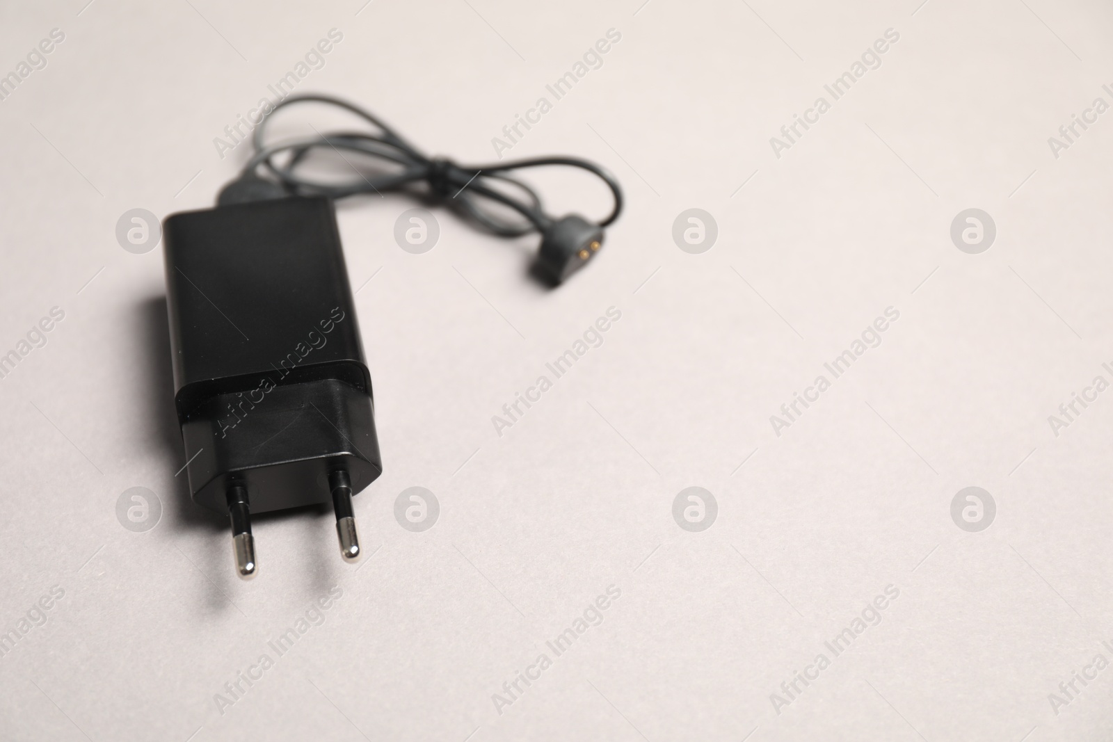 Photo of USB power adapter with charge cable on light grey background, closeup. Space for text