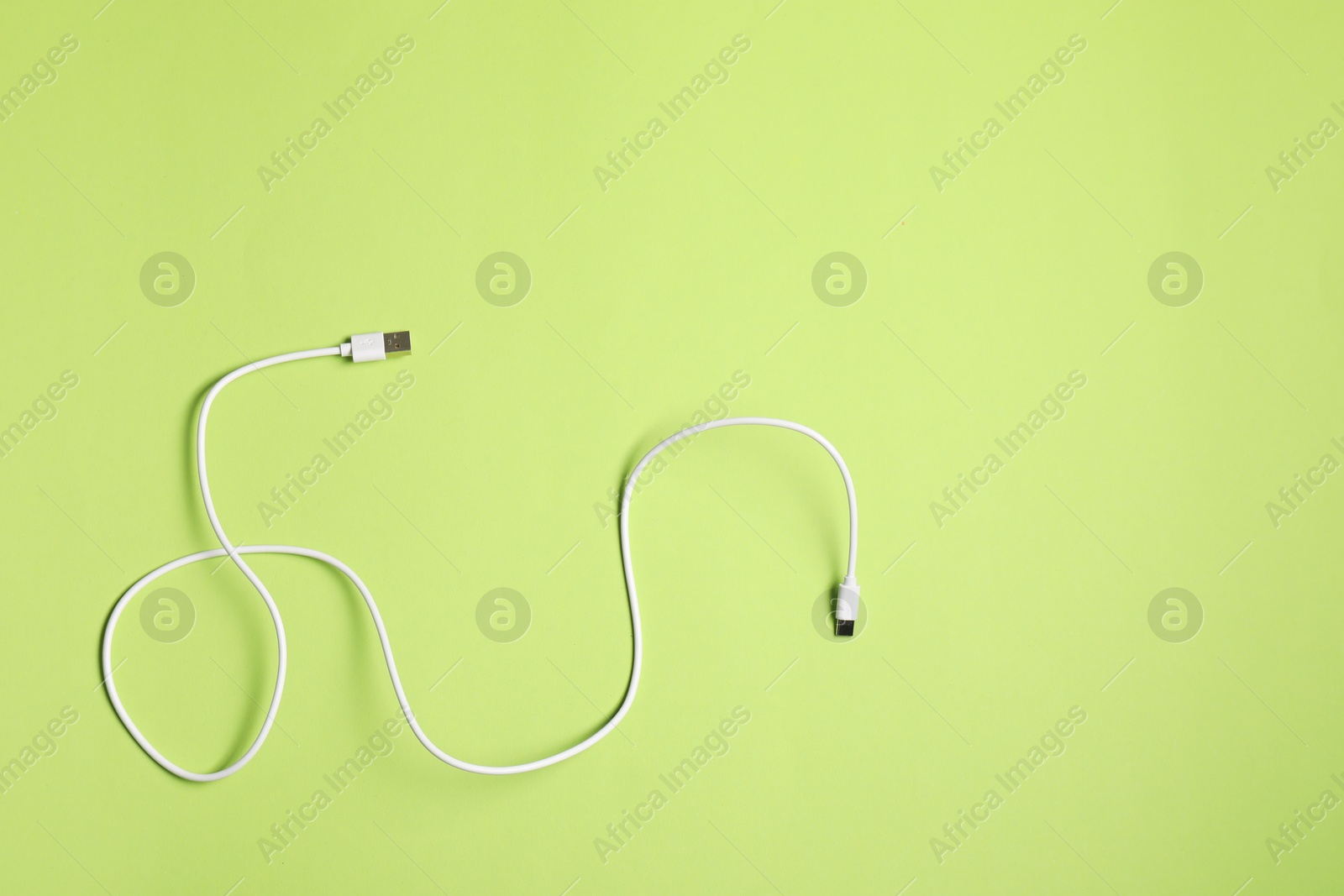 Photo of One USB charge cable on green background, top view.. Space for text