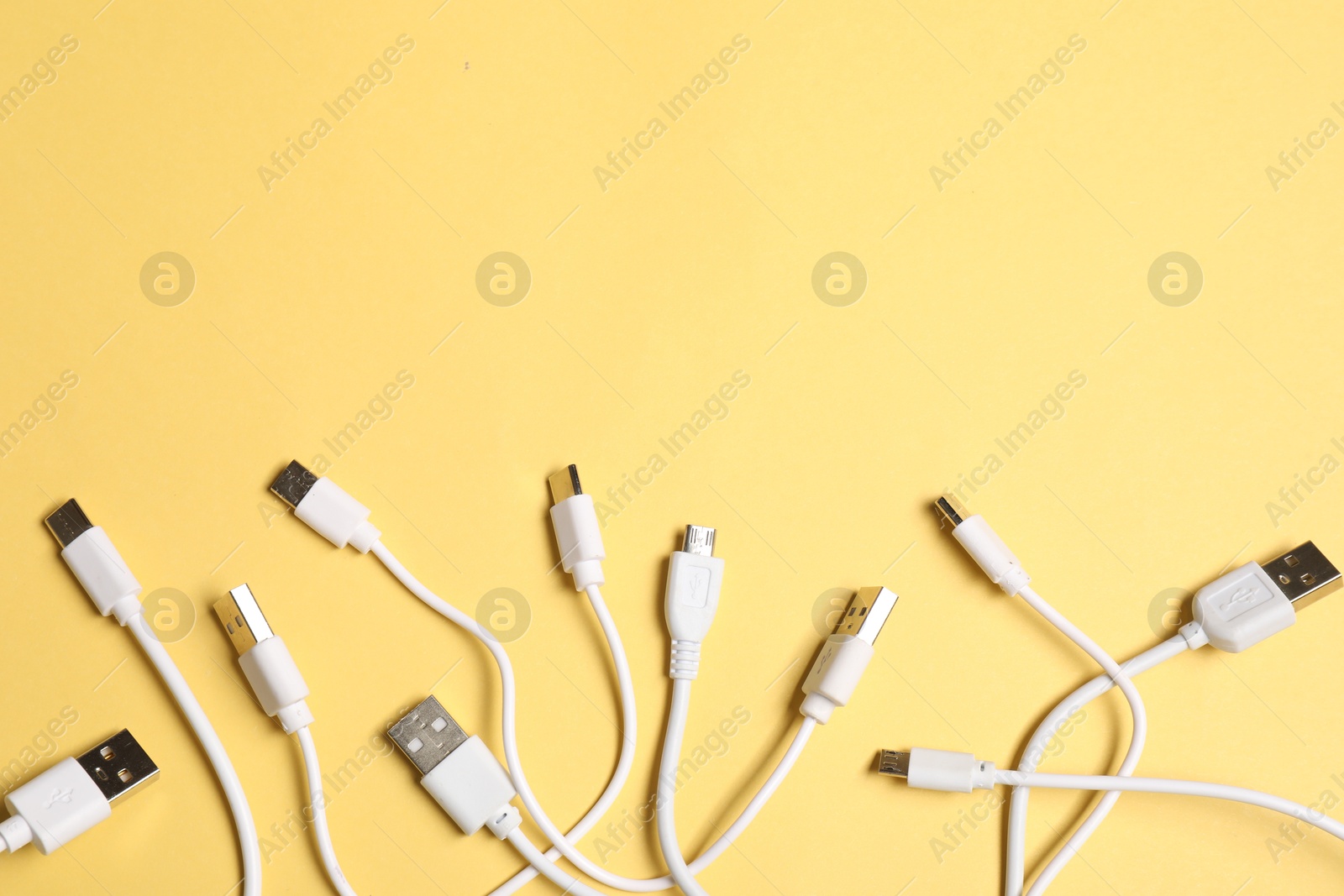 Photo of USB charge cables on yellow background, flat lay. Space for text