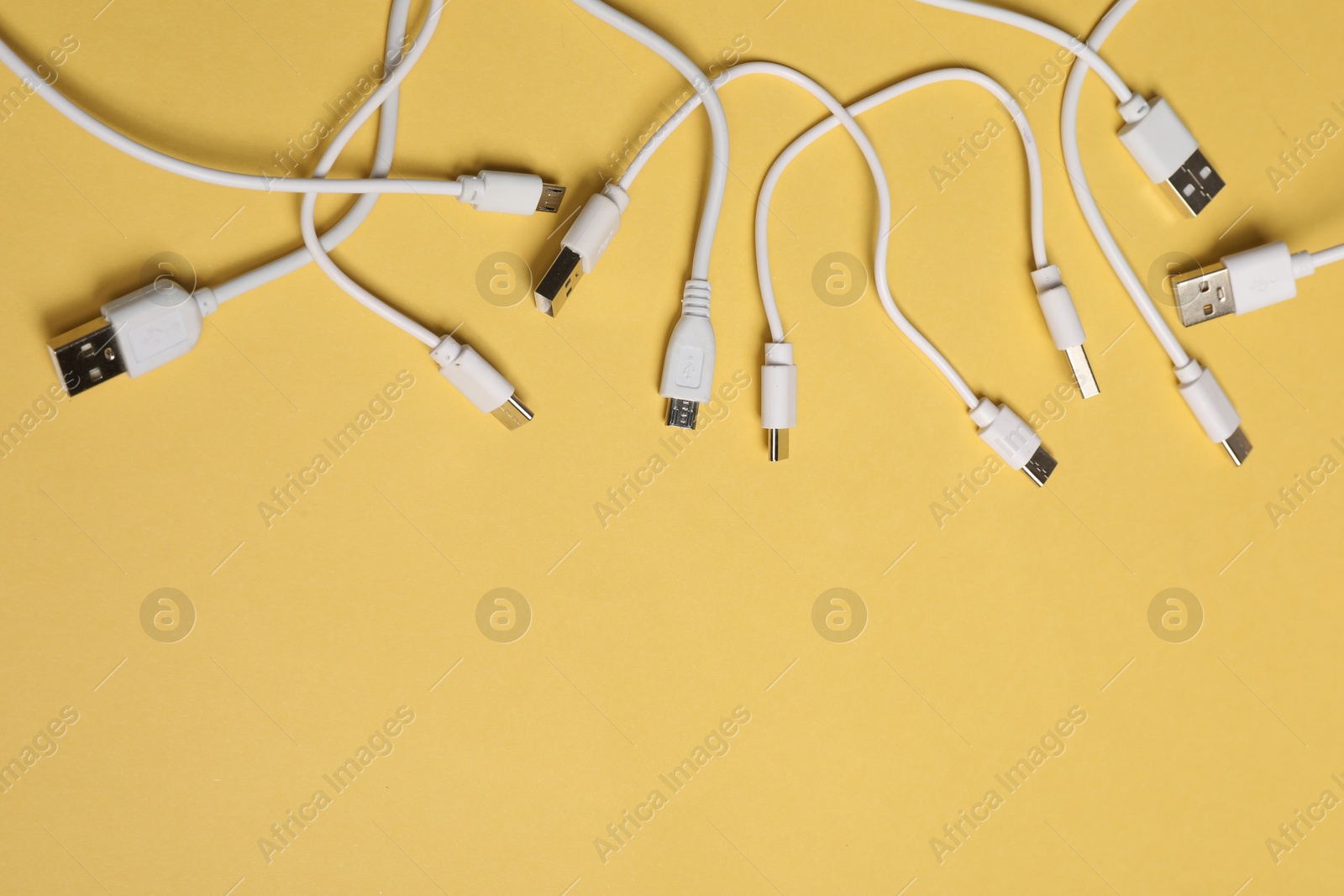 Photo of USB charge cables on yellow background, flat lay. Space for text