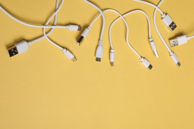 Photo of USB charge cables on yellow background, flat lay. Space for text