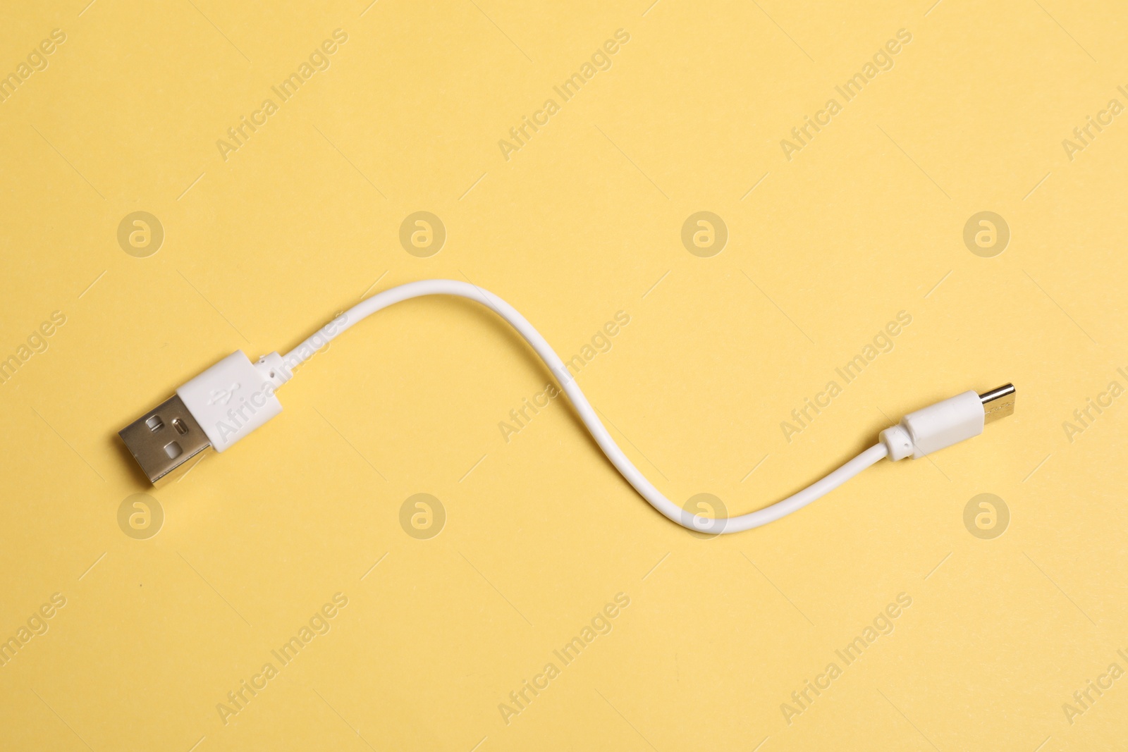 Photo of One USB charge cable on yellow background, top view