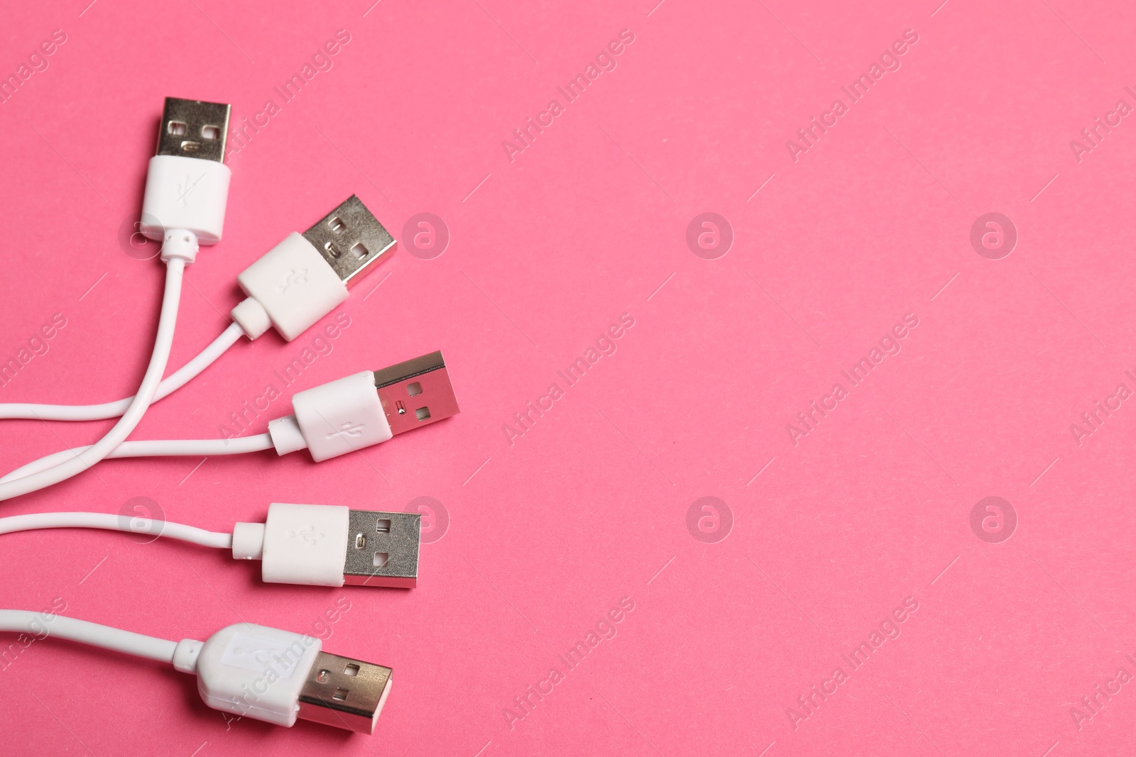 Photo of USB charge cables on pink background, flat lay. Space for text