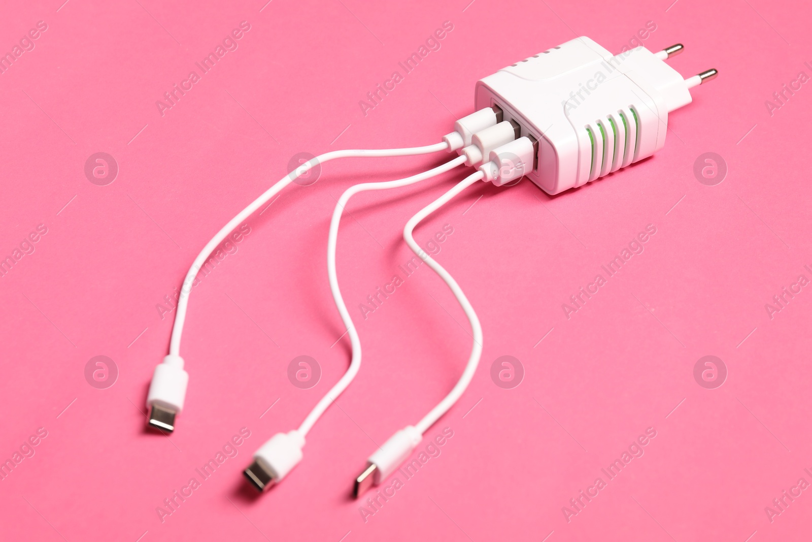 Photo of USB power adapter with charge cables on pink background, closeup