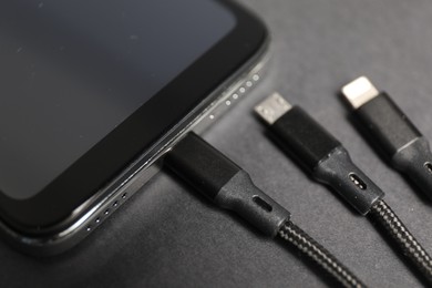 Photo of USB charge cable connected to smartphone on black background, closeup