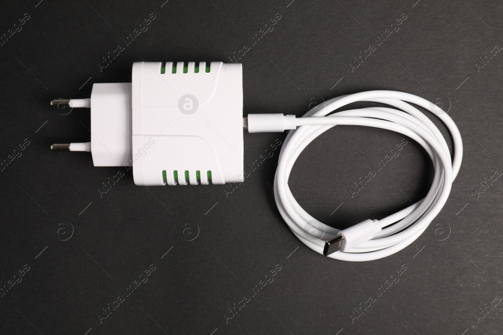 Photo of USB power adapter with charge cable on black background, top view