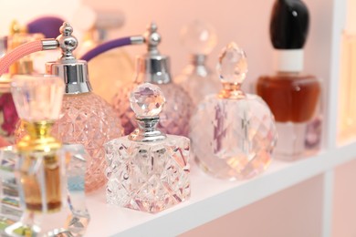 Photo of Different bottles of luxury perfume on shelf in store, closeup