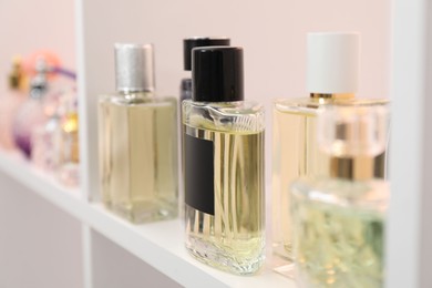 Different bottles of luxury perfume on shelf in store, closeup