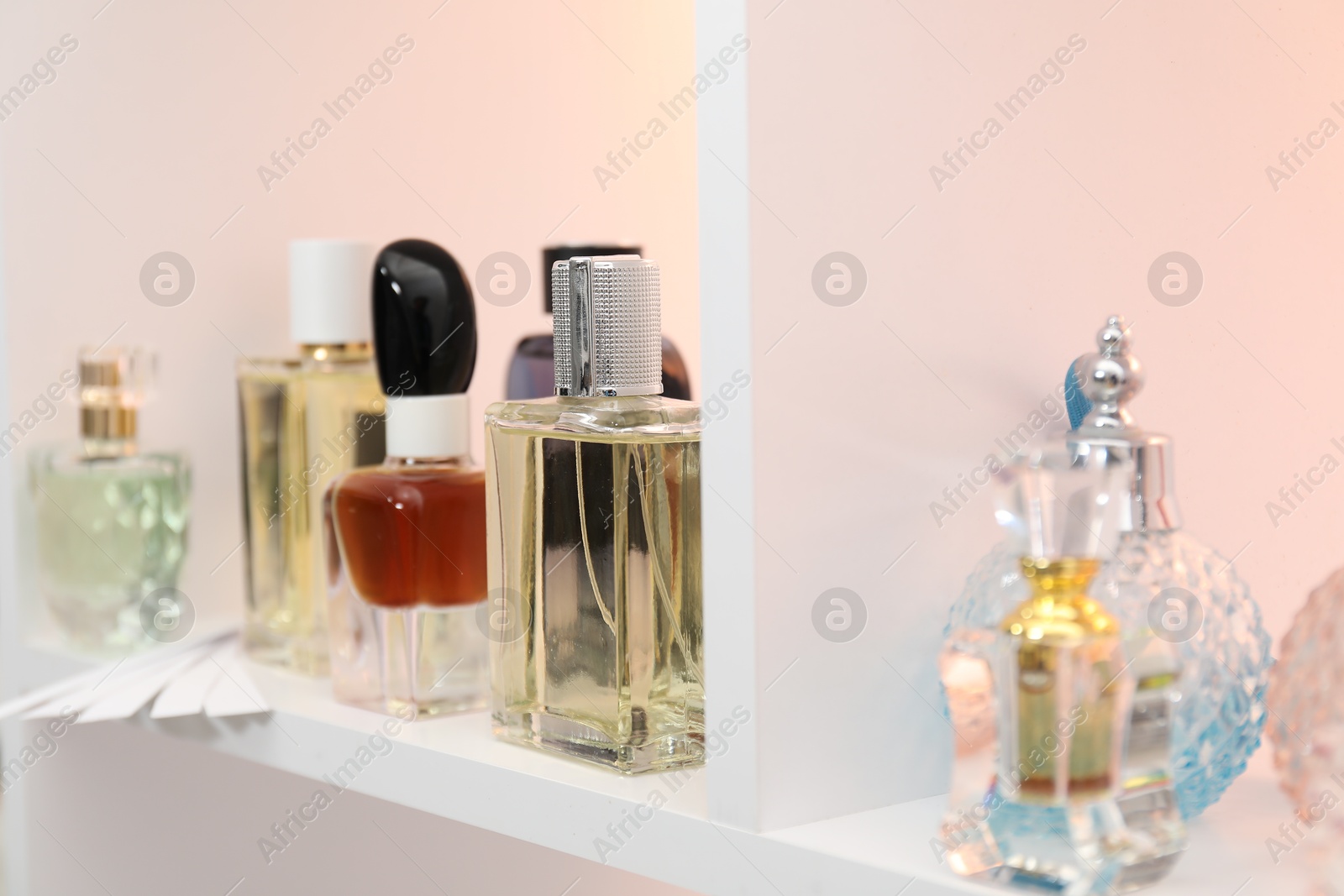 Photo of Different bottles of luxury perfume and fragrance blotters on shelf in store, closeup