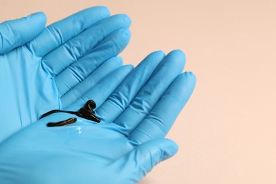 Photo of Doctor holding medicinal leeches on light pink background, closeup. Space for text