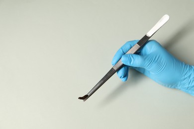 Photo of Doctor holding medicinal leech with tweezers on light grey background, top view. Space for text