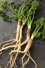 Photo of Parsley roots with leaves on black table, top view