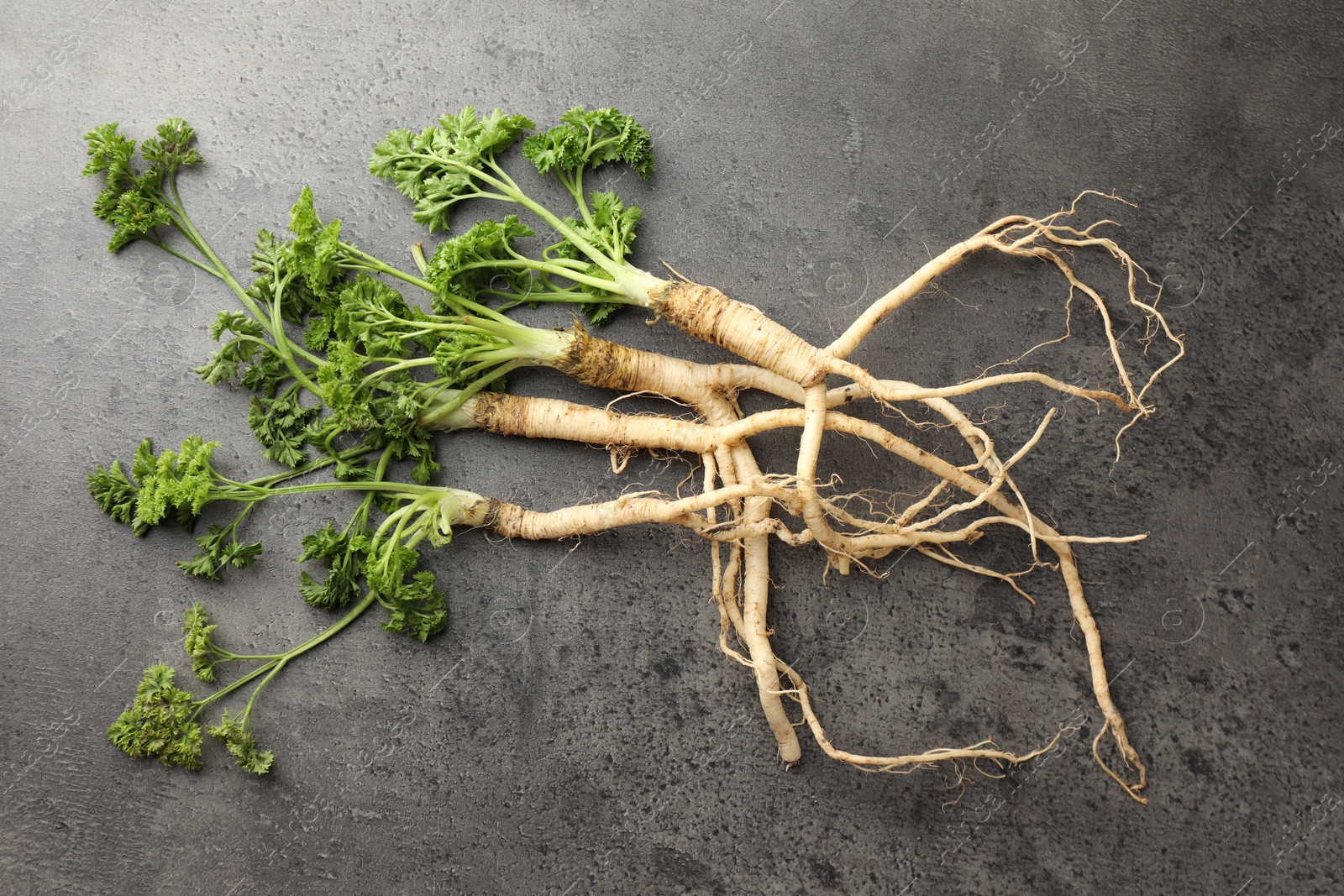 Photo of Parsley roots with leaves on black table, top view