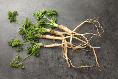 Photo of Parsley roots with leaves on black table, top view