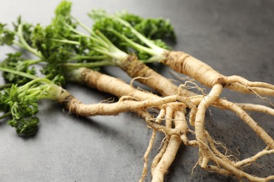 Photo of Parsley roots with leaves on black table, closeup