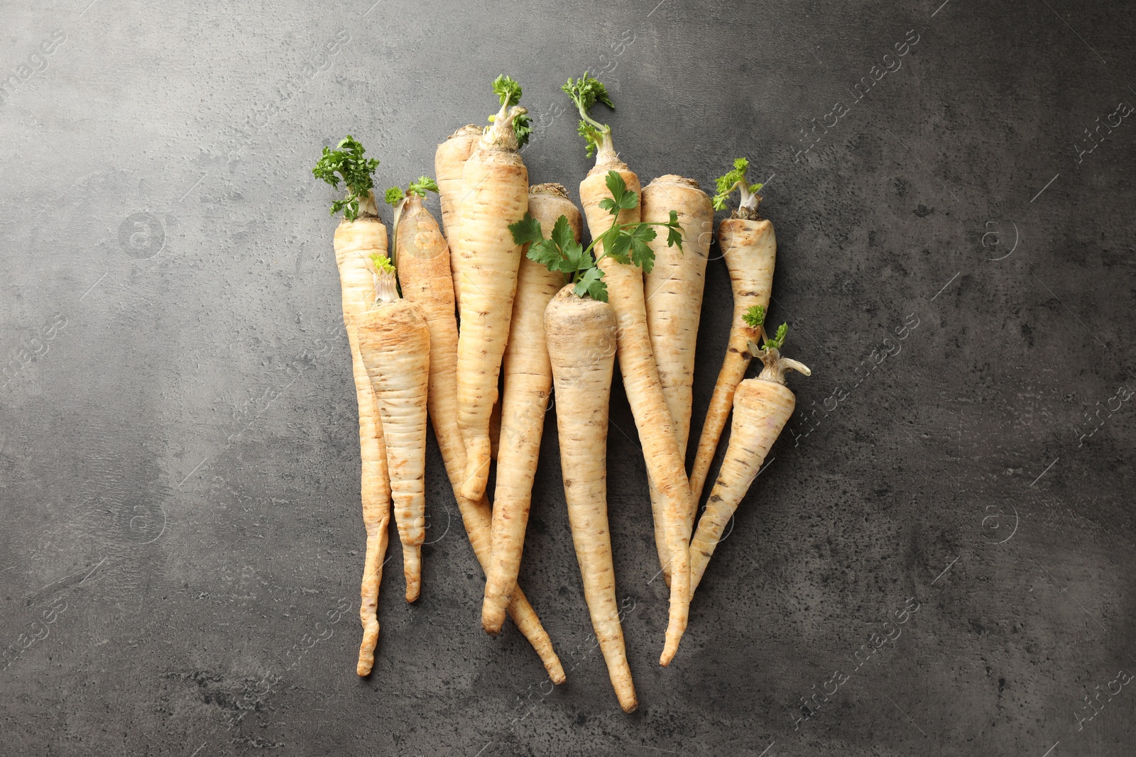 Photo of Parsley roots with leaves on black table, top view