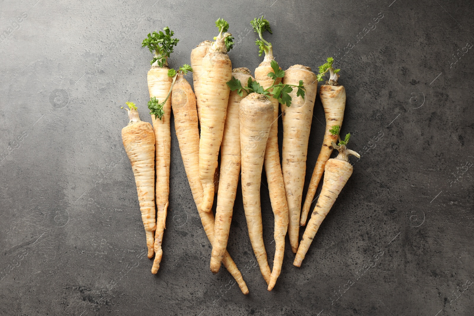 Photo of Parsley roots with leaves on black table, top view