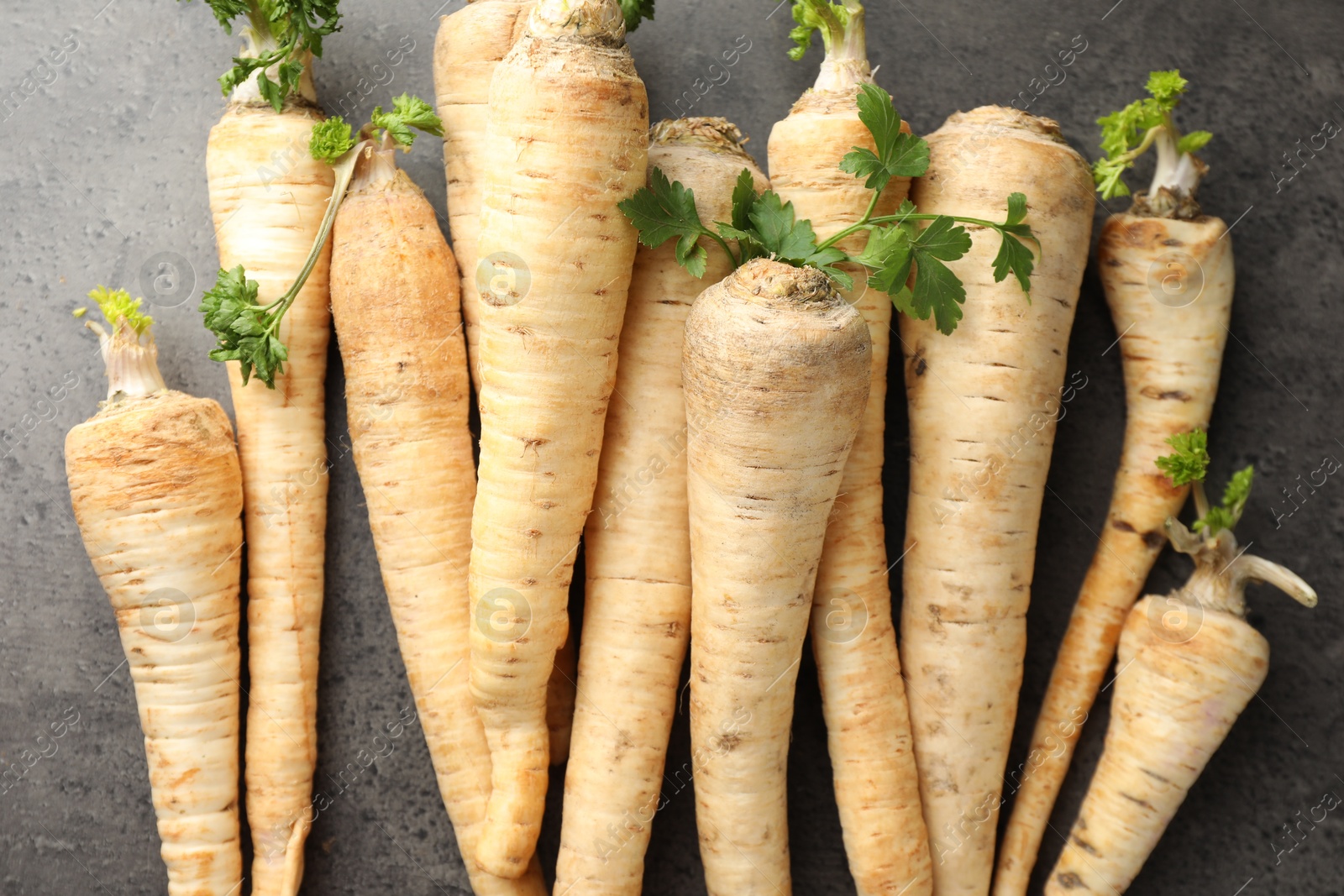 Photo of Parsley roots with leaves on black table, top view