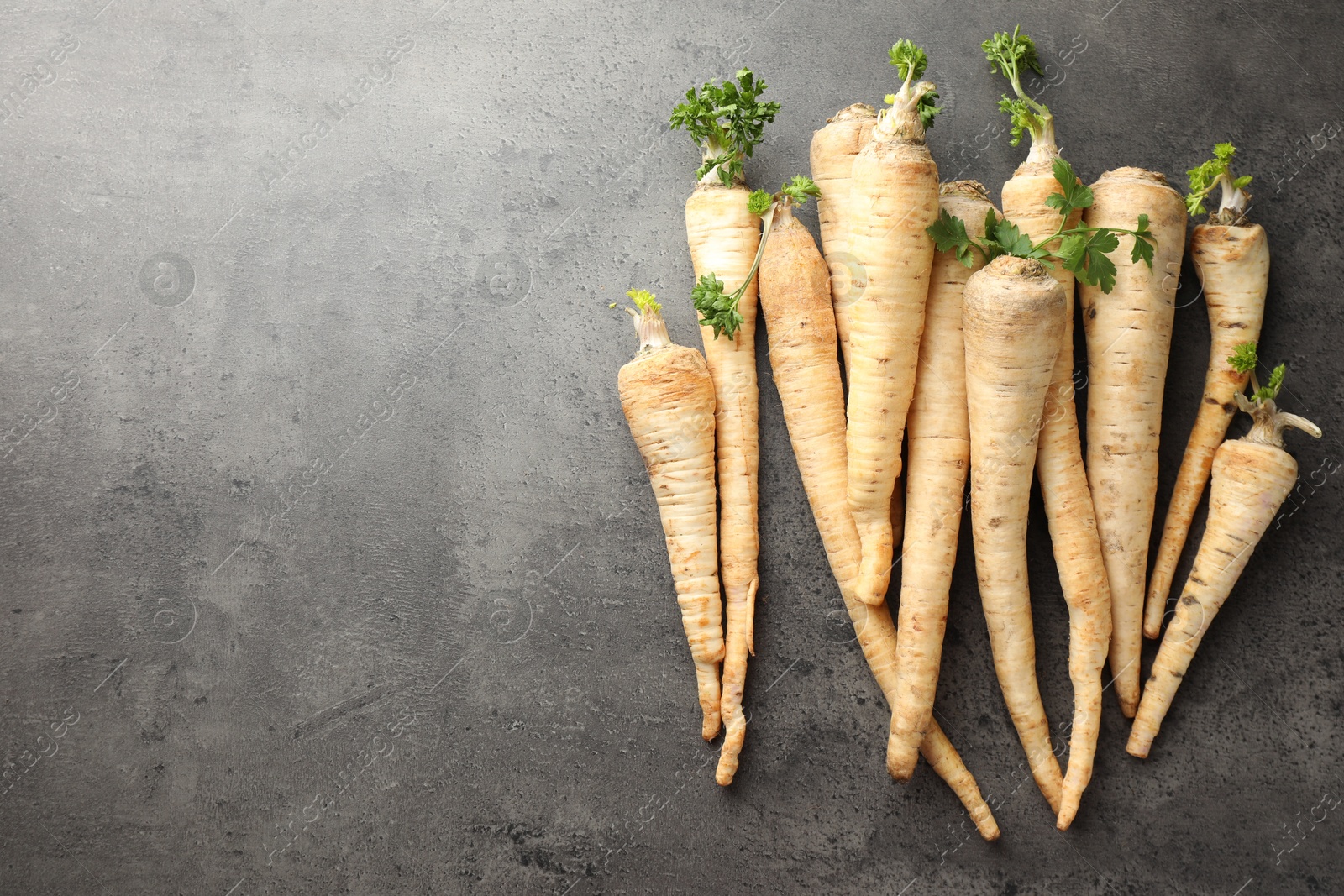 Photo of Parsley roots with leaves on black table, top view. Space for text