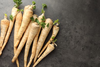 Photo of Parsley roots with leaves on black table, top view. Space for text