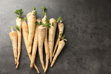 Photo of Parsley roots with leaves on black table, top view. Space for text