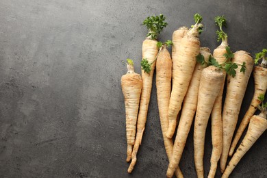 Photo of Parsley roots with leaves on black table, top view. Space for text