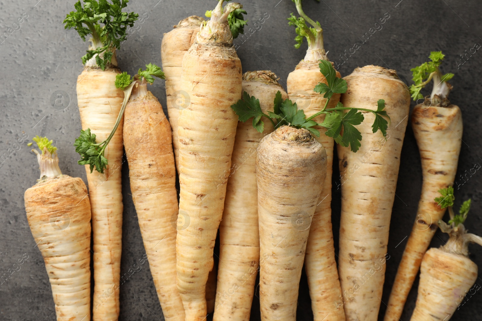 Photo of Parsley roots with leaves on black table, top view