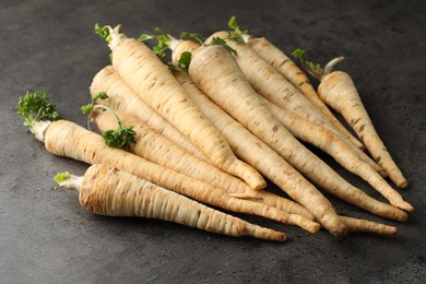 Photo of Parsley roots with leaves on black table, closeup