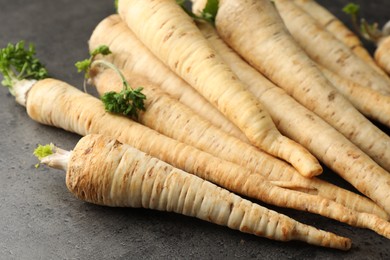 Photo of Parsley roots with leaves on black table, closeup