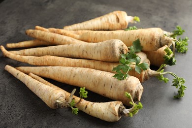 Photo of Parsley roots with leaves on black table, closeup