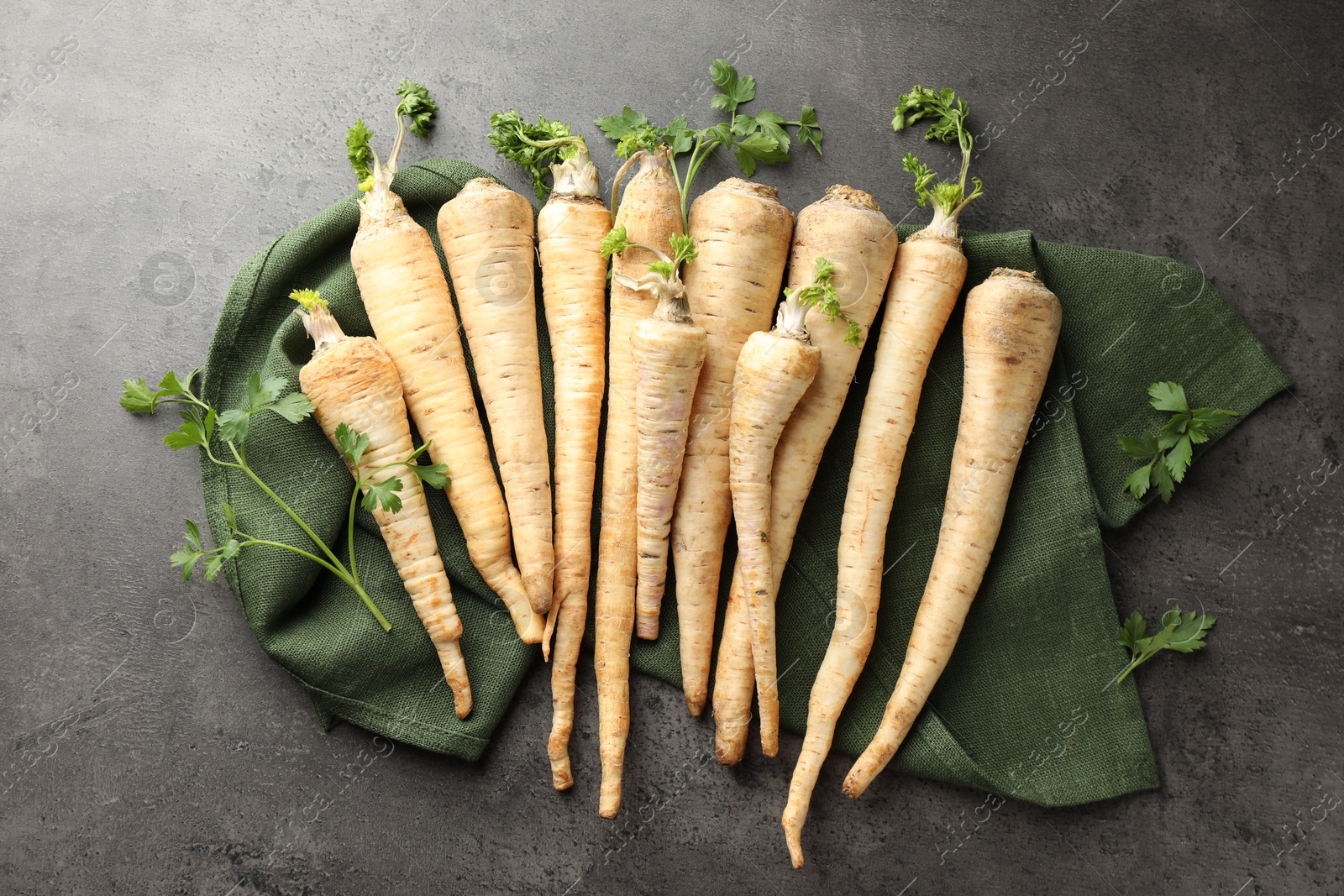 Photo of Parsley roots with leaves on black table, top view