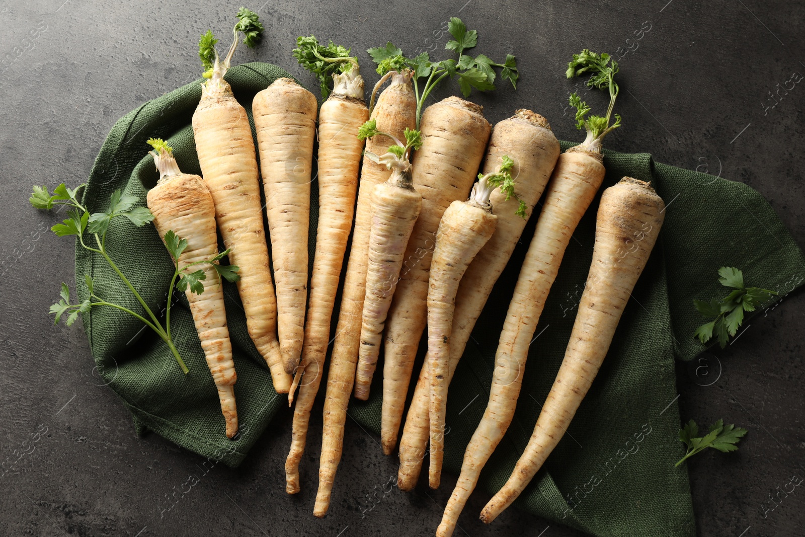 Photo of Parsley roots with leaves on black table, top view