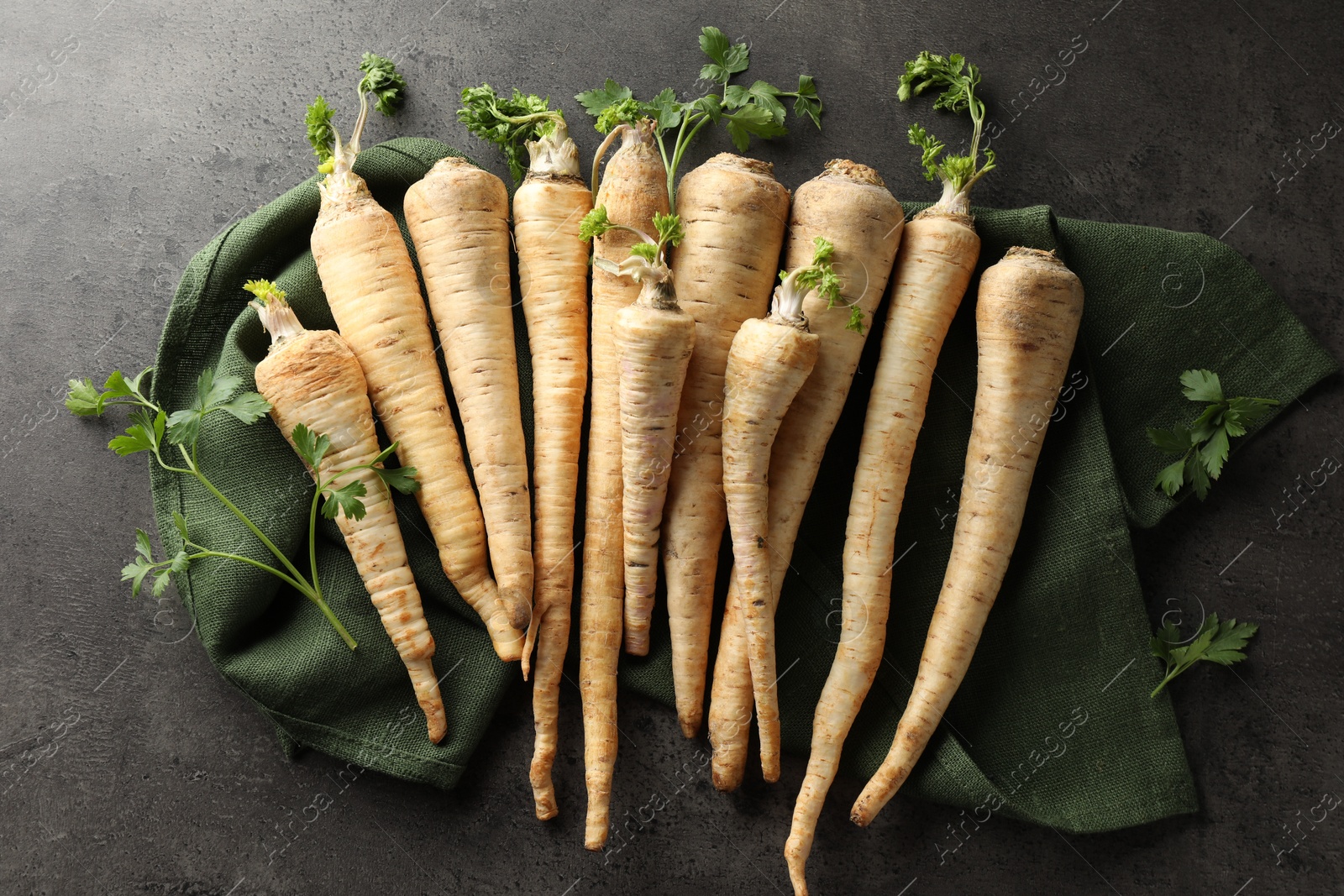 Photo of Parsley roots with leaves on black table, top view