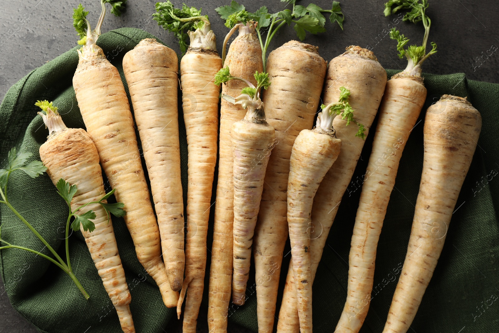 Photo of Parsley roots with leaves on black table, top view