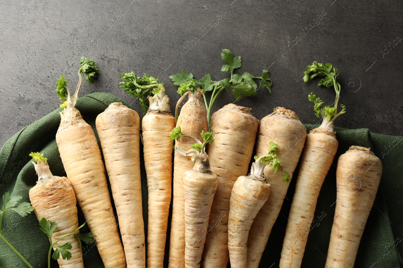 Photo of Parsley roots with leaves on black table, top view