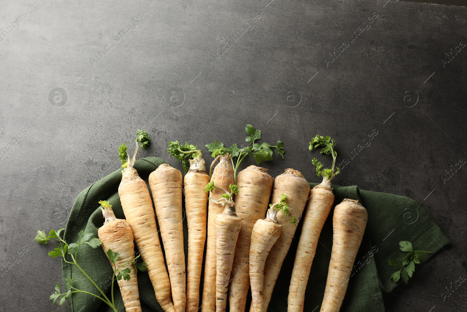 Photo of Parsley roots with leaves on black table, top view. Space for text