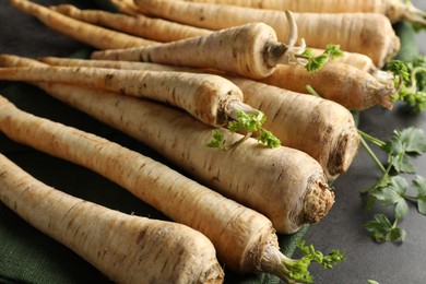 Photo of Parsley roots with leaves on black table, closeup