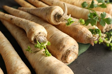 Photo of Parsley roots with leaves on black table, closeup