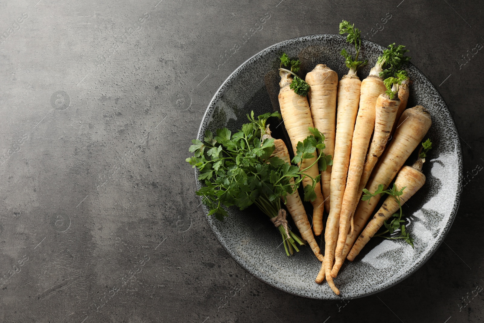 Photo of Parsley roots with leaves on black table, top view. Space for text