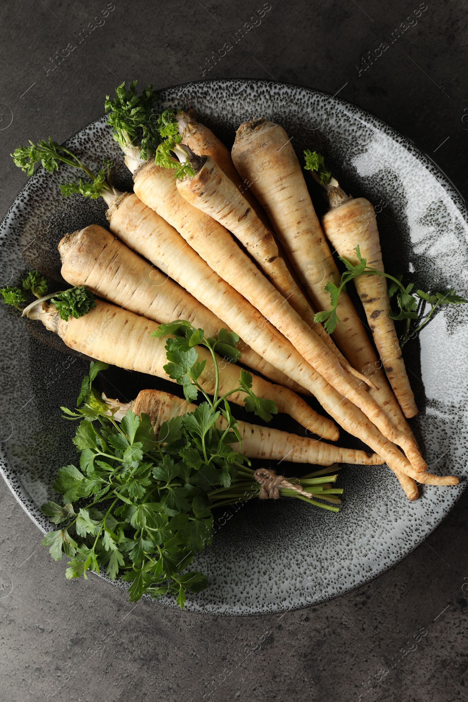 Photo of Parsley roots with leaves on black table, top view